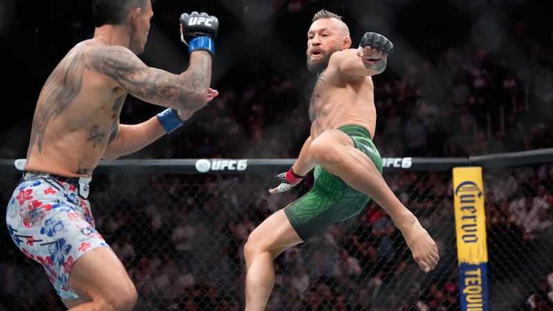 Conor McGregor, a la derecha, salta para dar una patada mientras pelea contra Max Holloway en...