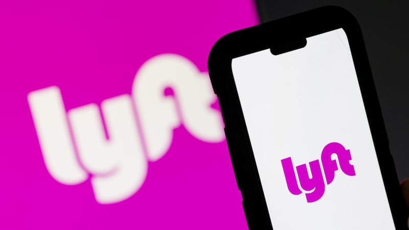 A photo of the Lyft logo, with a phone near it.