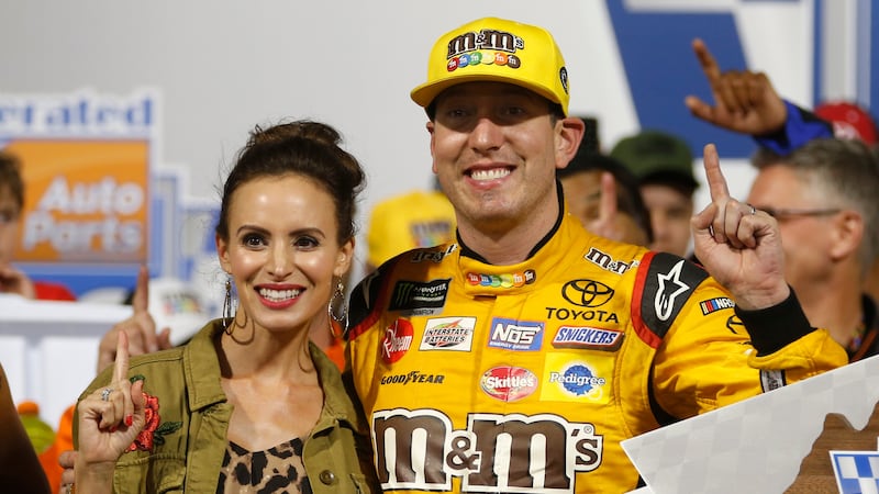 Kyle Busch (18) poses with the winners trophy and his wife, Samantha, as he celebrates winning...