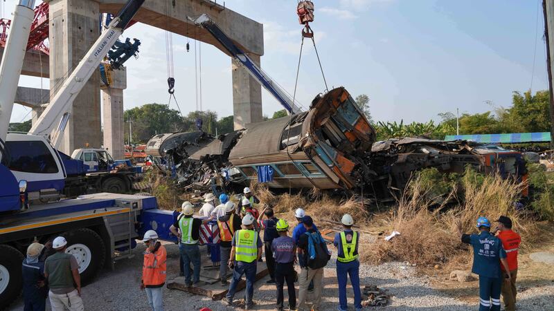 Rescatistas intentan levantar los restos después de que una grúa cayera sobre un tren de...