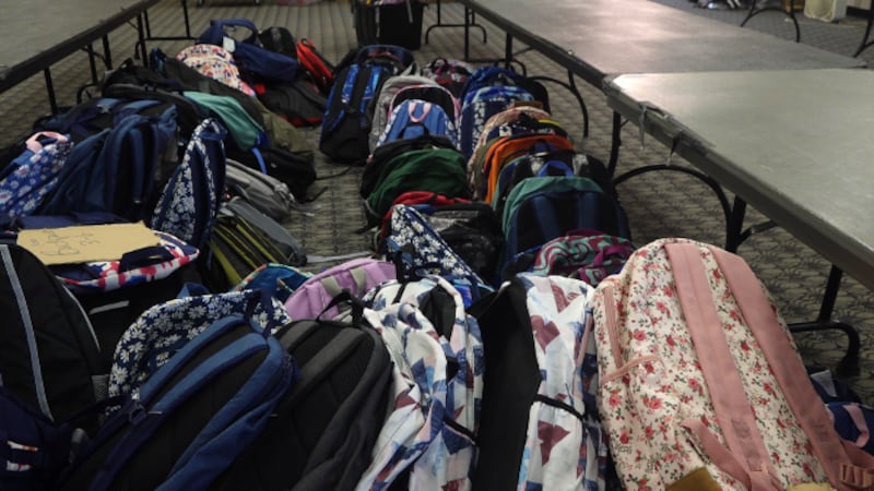 The backpacks to be picked up at the Augusta Civic Center are arranged by age group.