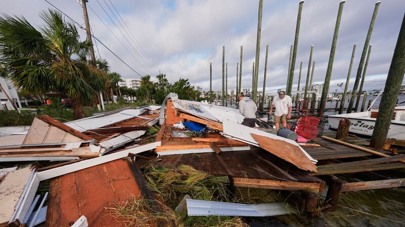 People retrieve belongings from a collapsed boat house in the aftermath of Hurricane Isaias in...