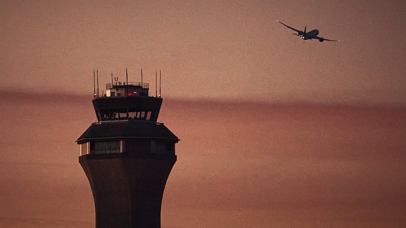FILE - A plane flies by a control tower at Newark Liberty International Airport on Nov. 7,...