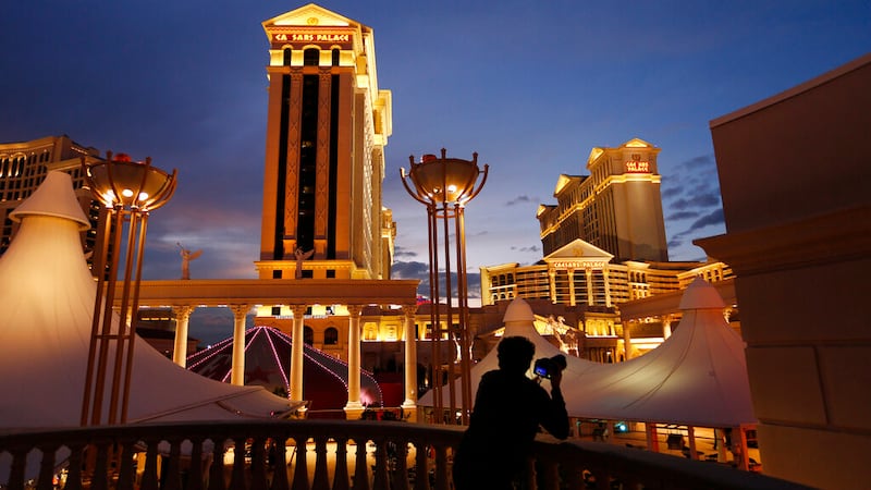 In this Jan. 12, 2015, file photo, a man takes pictures of Caesars Palace hotel and casino, in...