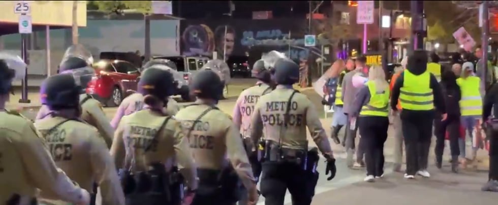Ambos lados de la calle estaban llenos de personas sosteniendo carteles y cantando, con la...